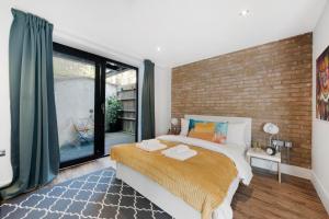 a bedroom with a brick wall and a large bed at Manor House Studios By Morethanstays in London