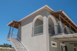 a white house with a staircase in front of it at Pine tree Apartment & sunset in Koiliomenos