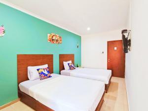 2 Betten in einem Zimmer mit grünen und weißen Wänden in der Unterkunft YUTAKA LG Dukuh Kupang in Surabaya