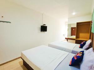 a bedroom with two beds and a tv on the wall at Yutaka Inn LG Dukuh Kupang in Surabaya