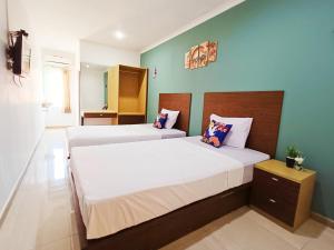 two beds in a small room with green walls at Yutaka Inn LG Dukuh Kupang in Surabaya