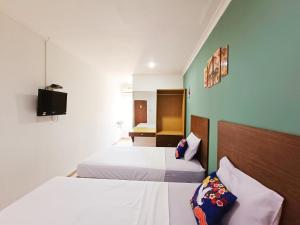 ein Hotelzimmer mit 2 Betten und einem TV in der Unterkunft YUTAKA LG Dukuh Kupang in Surabaya