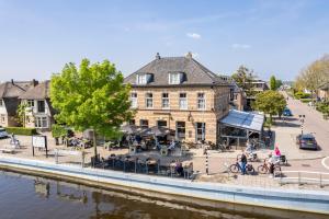 un edificio junto a un río con gente sentada en las mesas en Hotel Over de Brug, en Haastrecht