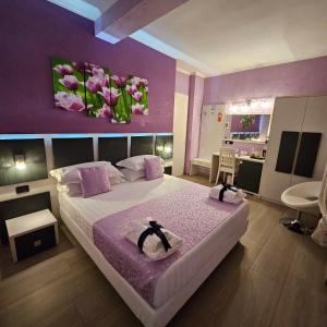 1 dormitorio con 1 cama grande y paredes moradas en Albis Rooms Guest House, en Fiumicino