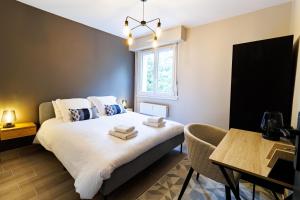 Un dormitorio con una cama y una mesa y una ventana. en Appartement moderne près de Genève, en Ferney-Voltaire