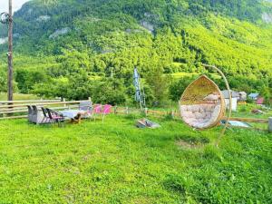 a group of chairs and tables in a field at Dedushi Guesthouse &Wood cabins-Camping place in Gusinje +37 photos