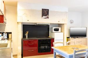 a small kitchen with red cabinets and a table at La Boutique Germain 4 à 6 personnes in Lacave +19 photos