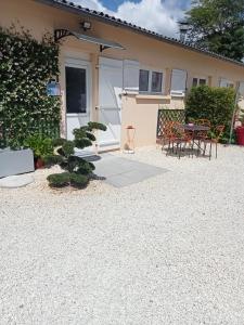 un patio con mesa y sillas frente a una casa en une pause quelque part au jardin des érables et des niwakis en Saint-Médard-de-Guizières