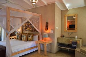 1 dormitorio con cama con dosel y lavamanos en Foxy Crocodile Bush Retreat & Kruger Safari's en Marloth Park