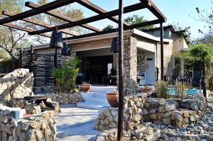 a house with a stone wall and a patio at Foxy Crocodile Bush Retreat & Kruger Safari's in Marloth Park