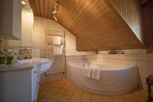 uma casa de banho com uma banheira grande e um lavatório em Ferienwohnungen im Boutique-Hotel Alpenrose em Schönried