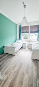 Duas camas num quarto com paredes azuis e pisos em madeira em Zweibettzimmer "Grün" in zentraler Lage em Bremen