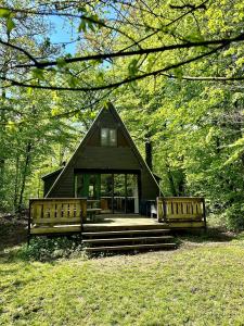 a small black cabin with a porch and two benches at Boseend Ardennen, Durbuy in Durbuy