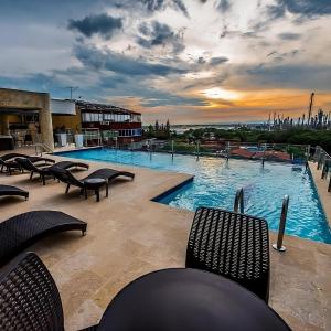 a swimming pool with chairs and a sunset in the background at Hotel Súper Estrellas in Barrancabermeja