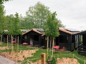 a row of black cabins with red chairs in a garden at wecamp Cudillero in El Pito