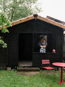 two people standing in the window of a black shack at wecamp Cudillero in El Pito