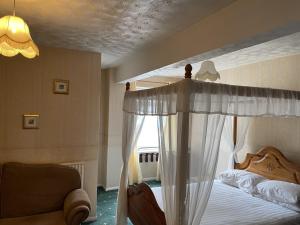 a bedroom with a canopy bed and a couch at Moorville Hall Hotel in Stoke on Trent