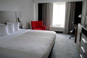 ein Hotelzimmer mit einem Bett und einem roten Stuhl in der Unterkunft Country Inn & Suites by Radisson, Council Bluffs, IA in Council Bluffs