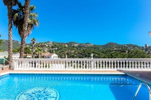 una piscina con una valla blanca y palmeras en Villa Natalia C101, en Lloret de Mar