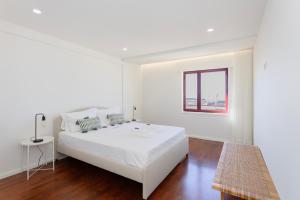 a white bedroom with a white bed and a window at Liiiving in Matosinhos - Seaside Balcony Apartment in Porto