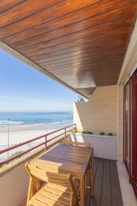 a balcony with a wooden table and a view of the beach at Liiiving in Matosinhos - Seaside Balcony Apartment in Porto