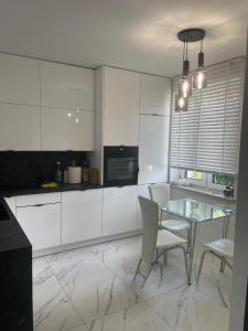 a kitchen with a glass table and white cabinets at Villa Klimontów in Klimontów