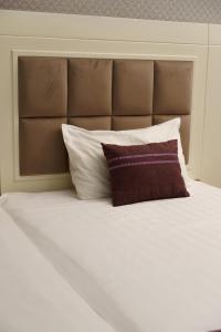 un letto con cuscini bianchi e testiera marrone di Safran Hotel a Baku