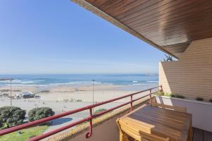a balcony with a wooden bench and the beach at Liiiving in Matosinhos - Seaside Balcony Apartment in Porto