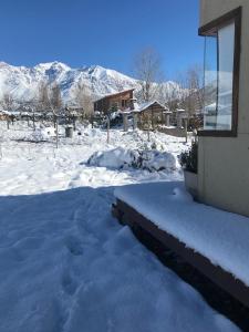 une cour recouverte de neige avec une maison et des montagnes dans l'établissement Casa de montaña, à Potrerillos