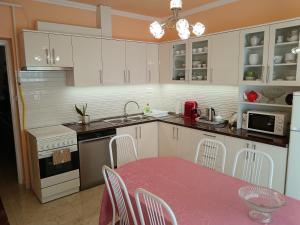 a kitchen with white cabinets and a table with chairs at Margó Vendégházak in Hajdúszoboszló