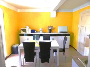 een keuken met een tafel en stoelen en gele muren bij Ferienwohnung Schweizer in Coswig