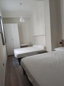 2 letti in una camera con pareti bianche di Appartamento "A2 passi" a Siderno Marina