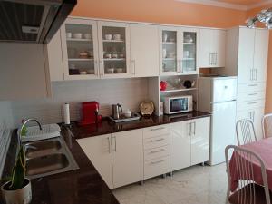 ハイドゥソボスローにあるMargó Vendégházakのキッチン(白いキャビネット、白い冷蔵庫付)
