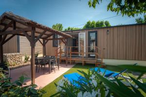 een huis met een terras en een tafel in een tuin bij CAMPING & SPA CAP SOLEIL in Vias