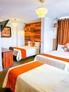 Habitación de hotel con 2 camas con sábanas de color naranja y blanco en Ayacucho Plaza en Ayacucho
