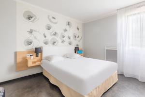 ランスにあるAppart'City Classic Reims Parc des Expositionsの白いベッドルーム(大型ベッド1台付)と壁に皿を配した客室です。