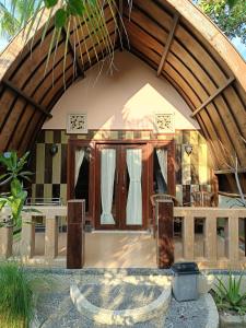 a house with a large arched entryway with a porch at Noby Gili Cottages in Gili Meno