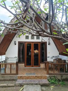 a house with a wooden door and a tree at Noby Gili Cottages in Gili Meno