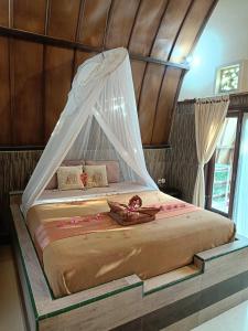 a bedroom with a bed with a mosquito net at Noby Gili Cottages in Gili Meno