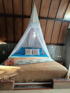 a bed with a canopy in a room at Noby Gili Cottages in Gili Meno