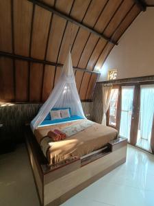 a bed with a canopy in a room with windows at Noby Gili Cottages in Gili Meno