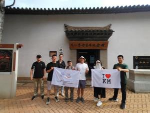 Kunming Upland International Youth Hostel في كونمينغ: مجموعة من الرجال يحملون لافتات أمام المبنى