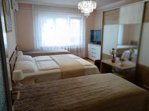 a bedroom with three beds and a window and a chandelier at Margó Vendégházak in Hajdúszoboszló