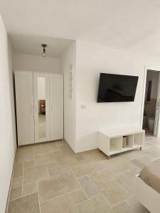 een woonkamer met een televisie en een tegelvloer bij Le Carrube Rooms in Peschici