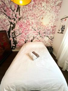 Un dormitorio con una cama blanca con flores rosas en la pared en Evasion dépaysante en bord de Garonne en Toulouse