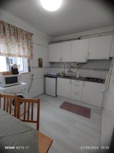una piccola cucina con armadi bianchi e tavolo di Apartamentos das Avós-Flor a Nazaré