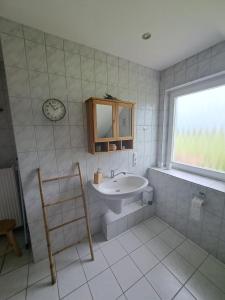 ein Badezimmer mit einem Waschbecken und einer Uhr an der Wand in der Unterkunft Haus Eufalia in Blankenheim