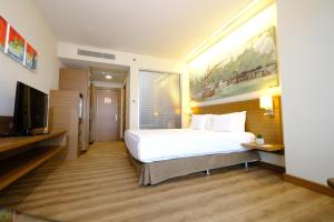 a bedroom with a large white bed and a flat screen tv at Gorrion Hotel Istanbul in Istanbul