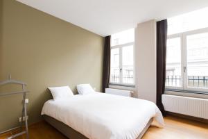 布魯塞爾的住宿－Smartflats - Monnaie，卧室配有白色的床和2扇窗户。