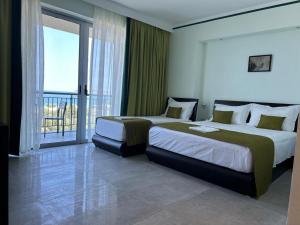 a hotel room with two beds and a balcony at Hotel Borshi in Borsh